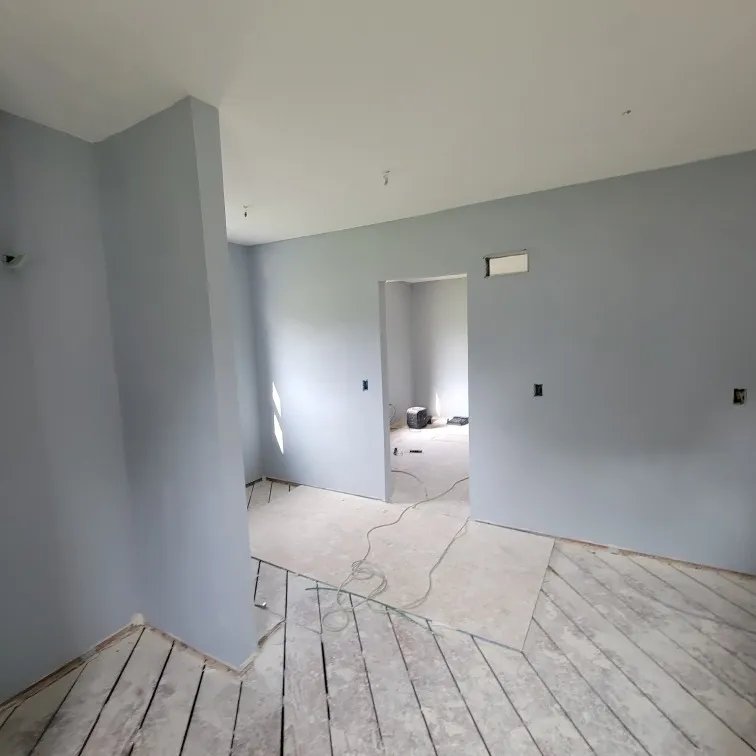 Residential home interior under structural reconstruction with newly hung drywall and bare subfloor.